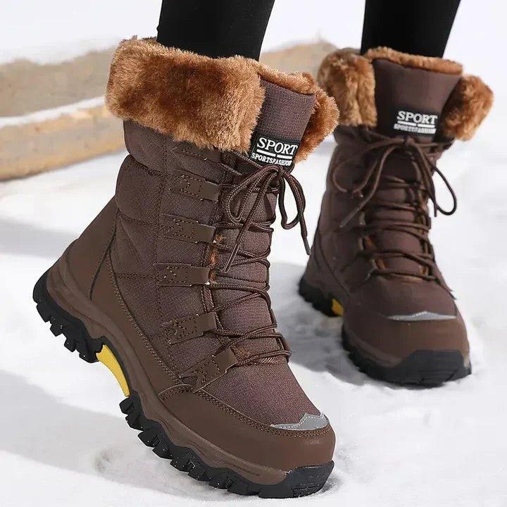 Front view of brown faux fur lined snow boots worn on feet in snow.