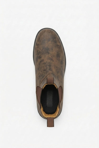 A single distressed brown leather Chelsea boot is shown from a top-down perspective on a white background.