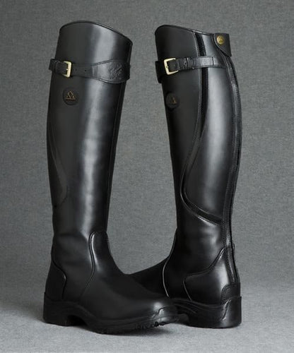 A pair of black tall riding boots with buckle details and zippers, standing upright in a studio setting.