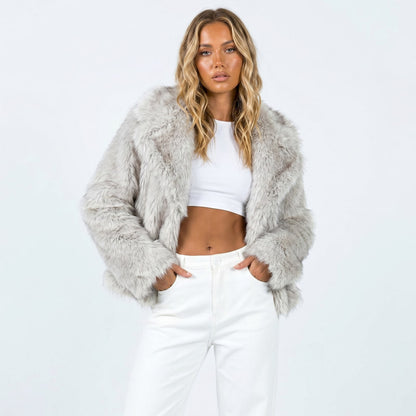 Front view of a woman wearing a light grey cropped faux fur jacket over a white crop top and white pants.