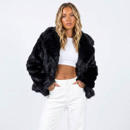 Front view of a woman wearing a black cropped faux fur jacket over a white crop top and white pants.