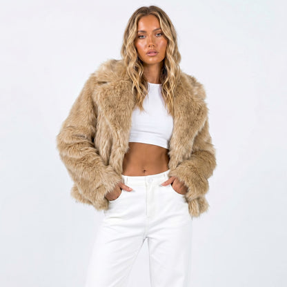 Front view of a woman wearing a tan cropped faux fur jacket over a white crop top and white pants.