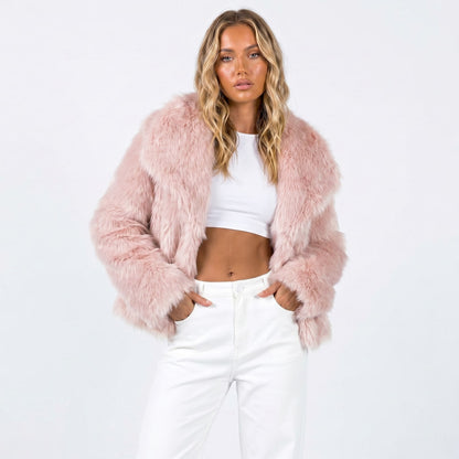 Front view of a woman wearing a light pink cropped faux fur jacket over a white crop top and white pants.