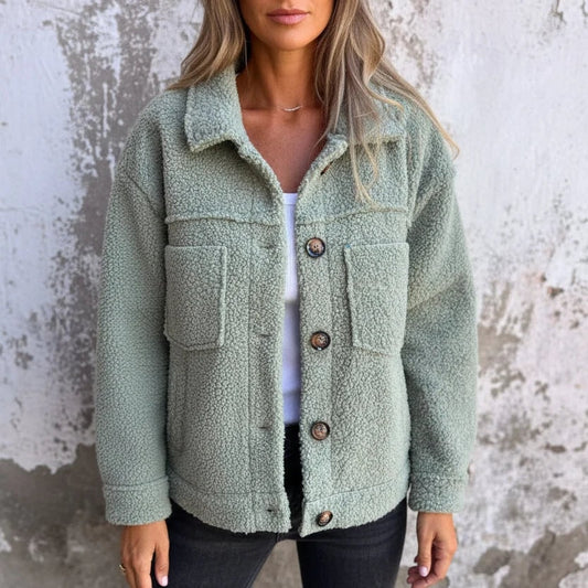Front view of a woman wearing a light green sherpa fleece shacket with a white top and dark jeans.