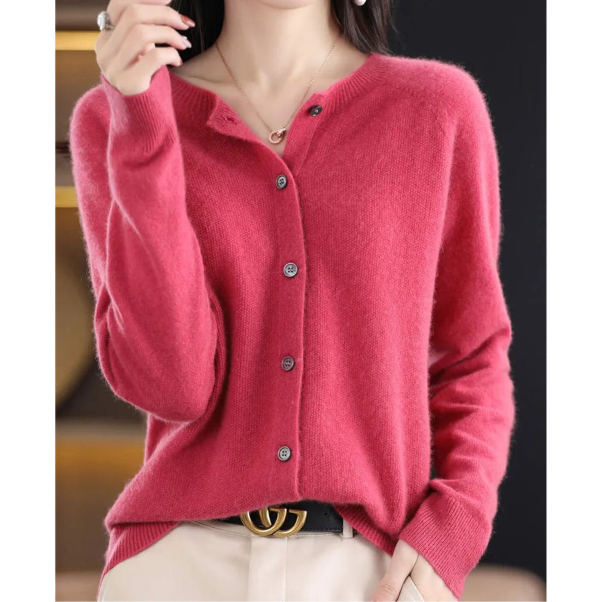 Front view of a woman wearing a pink fine knit button-front cardigan, styled with the top button undone.