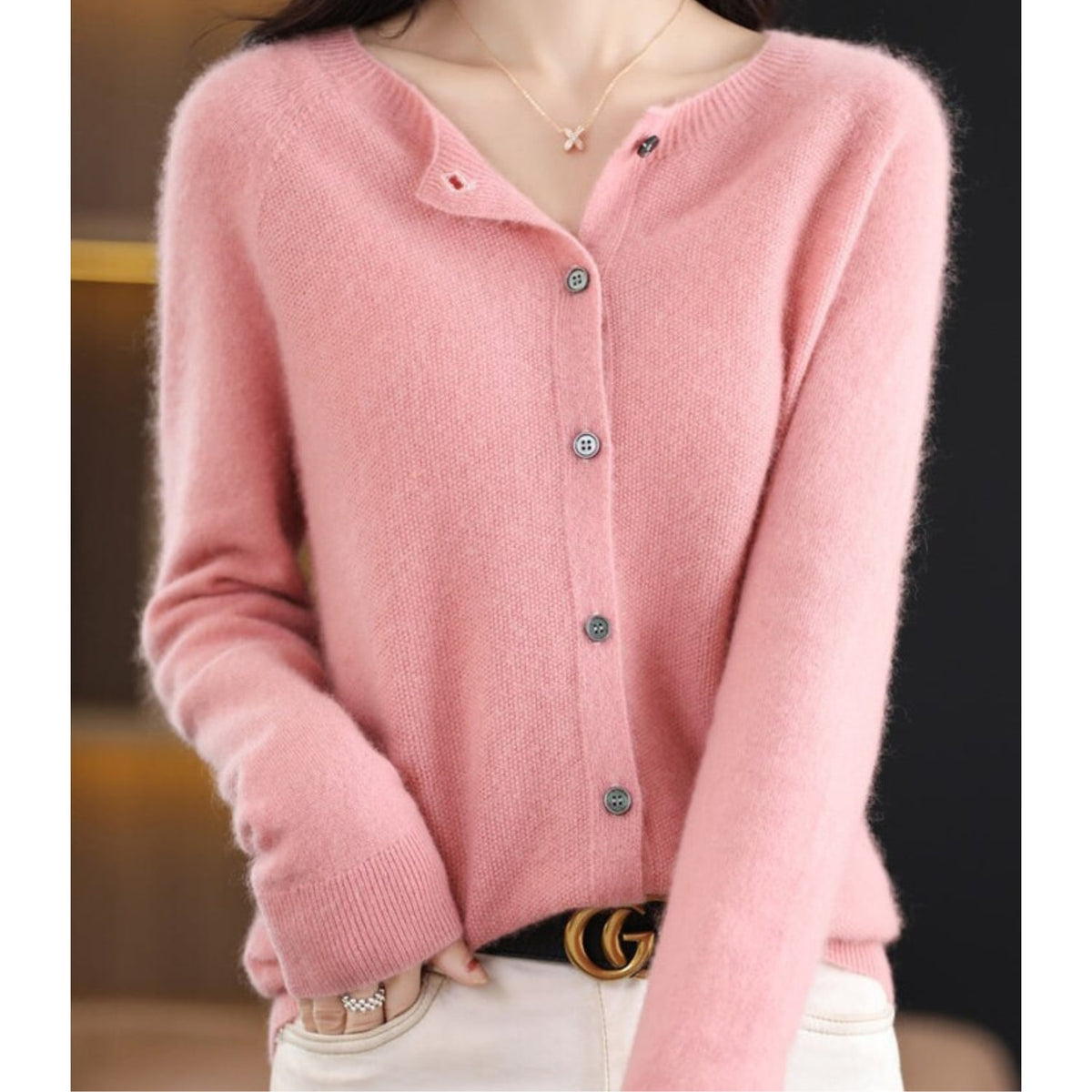 Front view of a woman wearing a light pink fine knit button-front cardigan, styled with the top button undone.