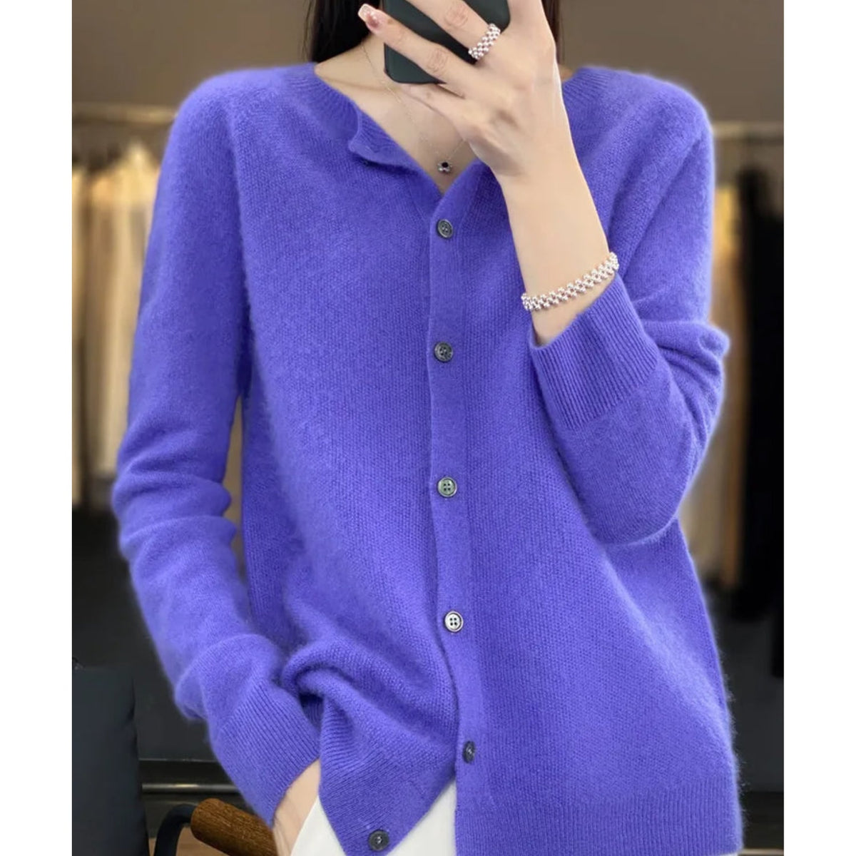 Front view of a woman wearing a purple fine knit button-front cardigan, with hands in pockets.