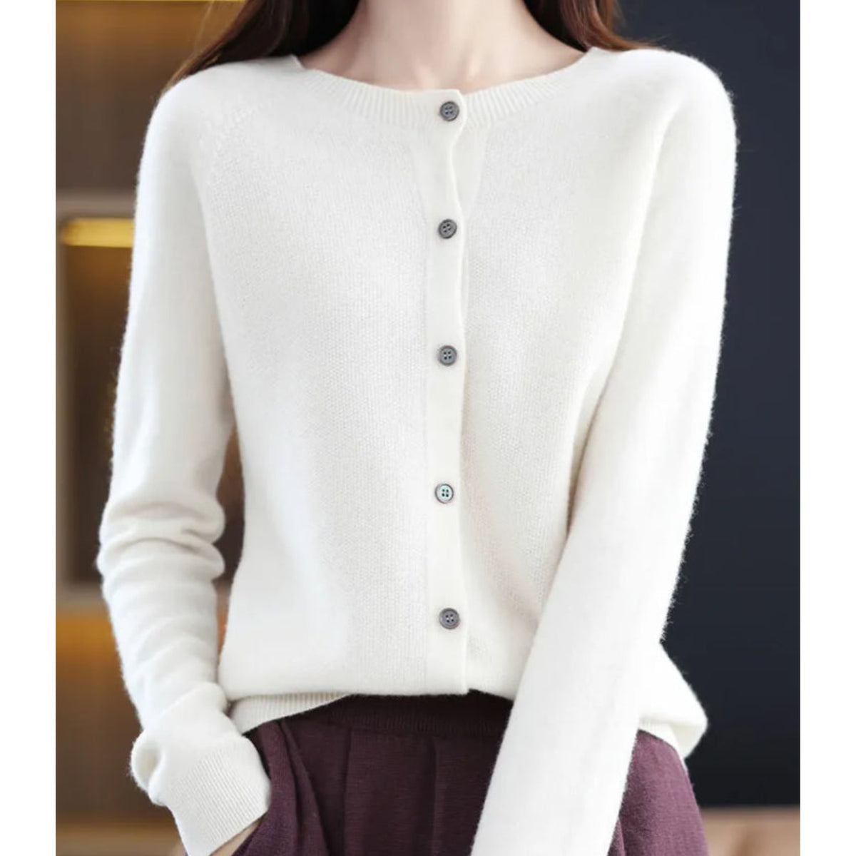 Front view of a woman wearing a white fine knit button-front cardigan, with all buttons fastened.