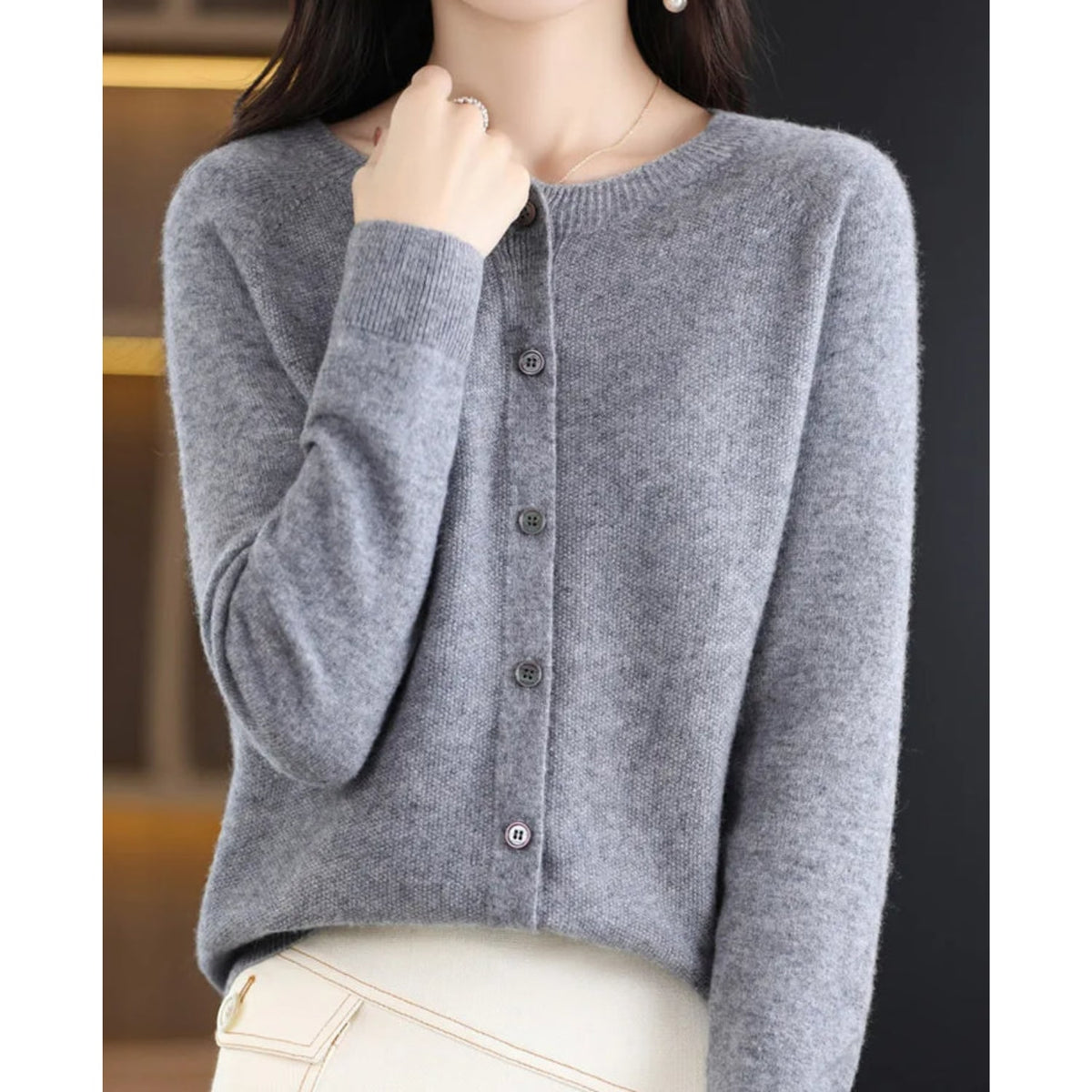 Front view of a woman wearing a grey fine knit button-front cardigan, with all buttons fastened.