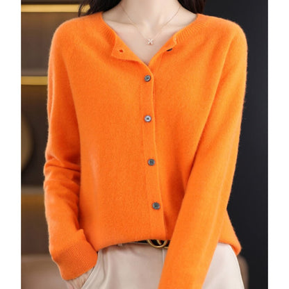 Front view of a woman wearing an orange fine knit button-front cardigan, styled with the top button undone.