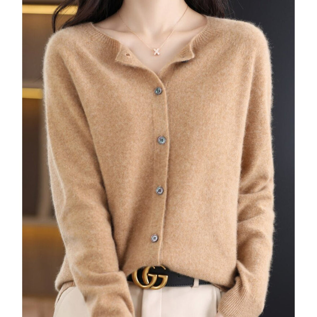 A model wears a tan button-up cardigan with a gold GG belt buckle.
