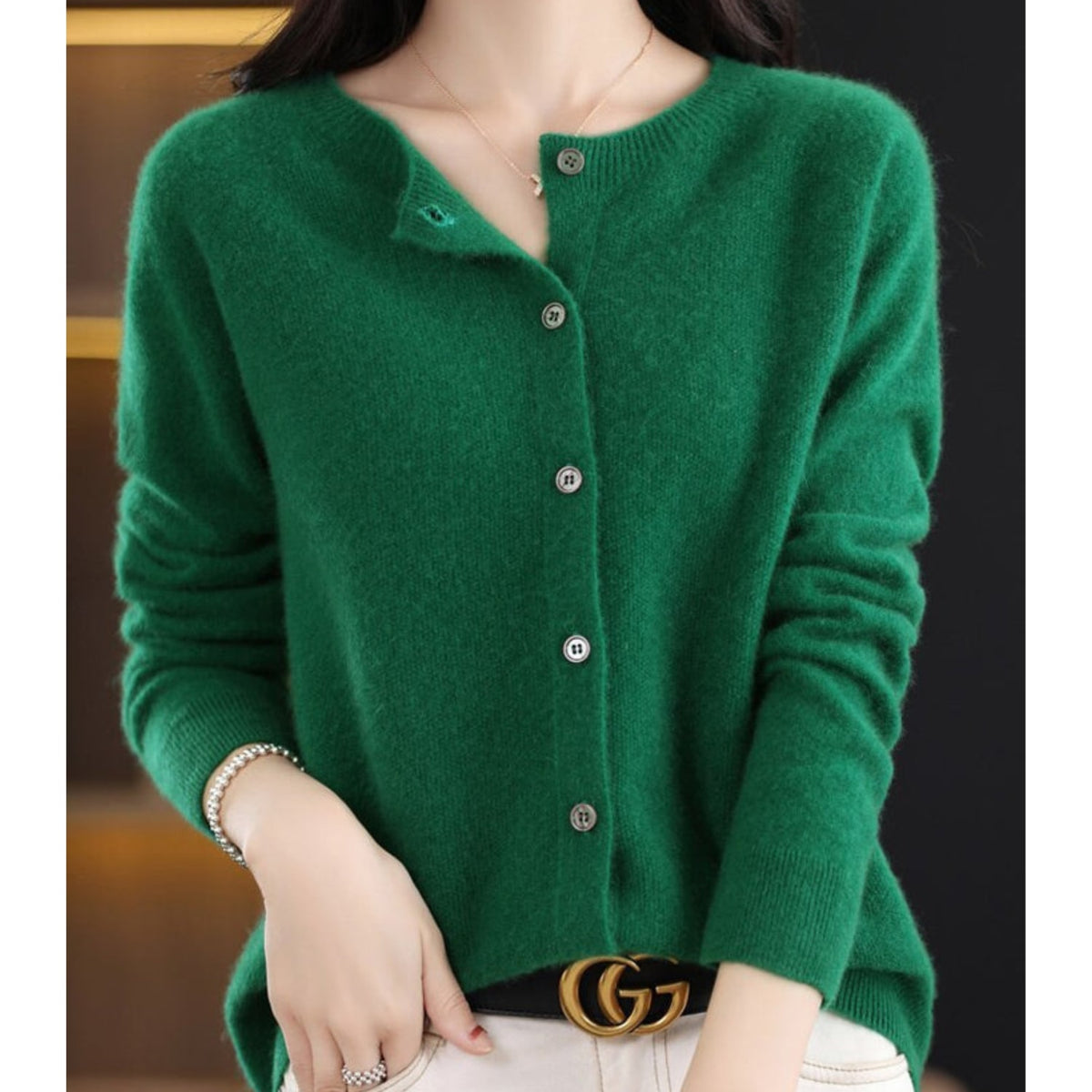A model wears a green button-up cardigan with a gold GG belt buckle.