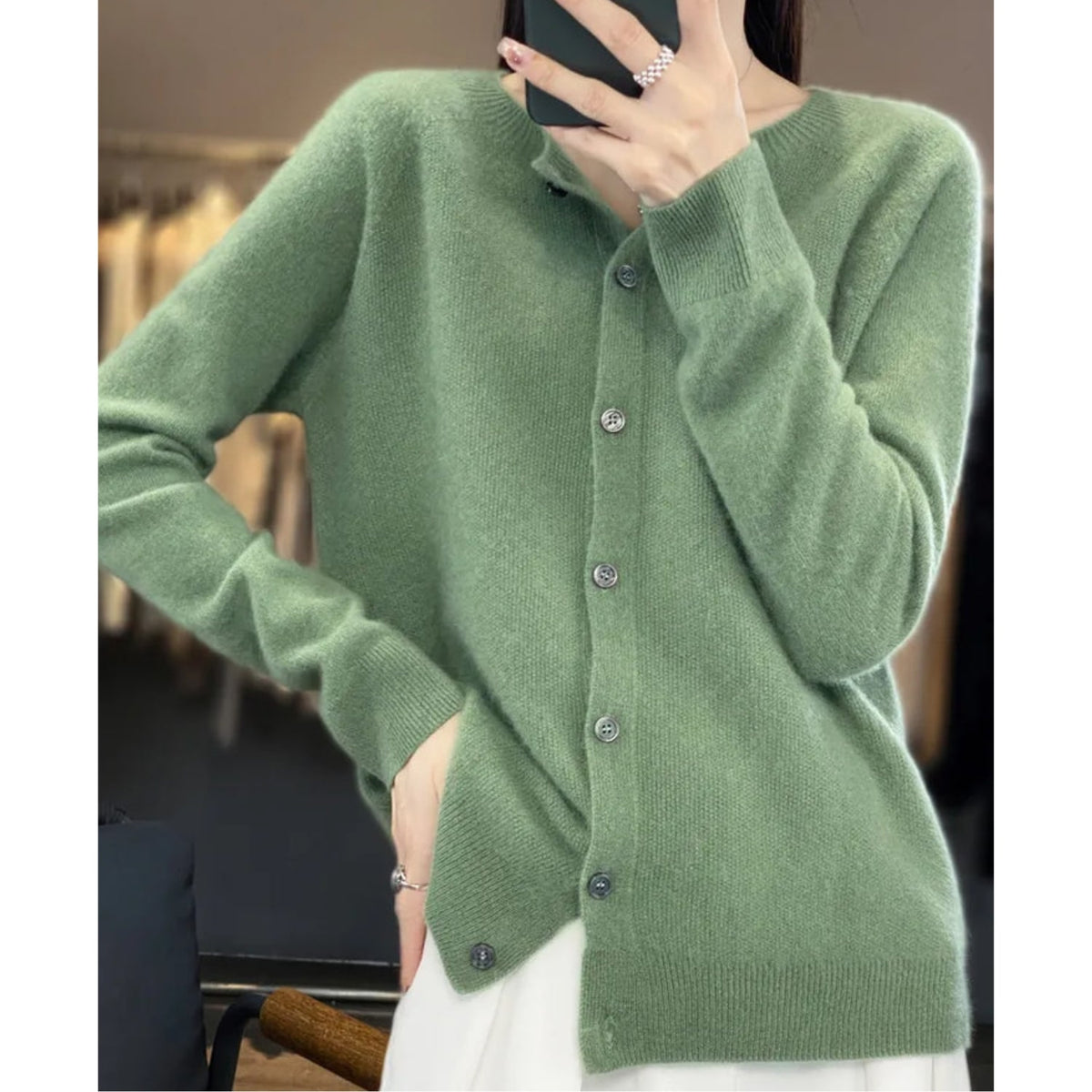 A model poses wearing a light green button-up cardigan.