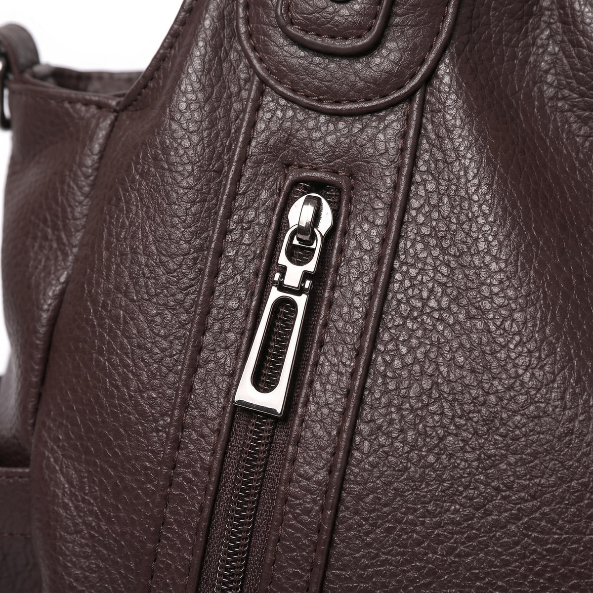 Close-up detail of the silver-tone zipper and pebbled faux leather texture on the front of the dark brown hobo bag.
