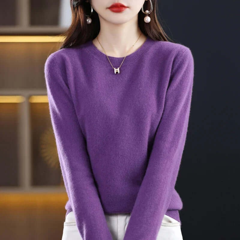 A model wears a purple long-sleeved crew neck sweater, accessorized with a gold 'H' pendant necklace.
