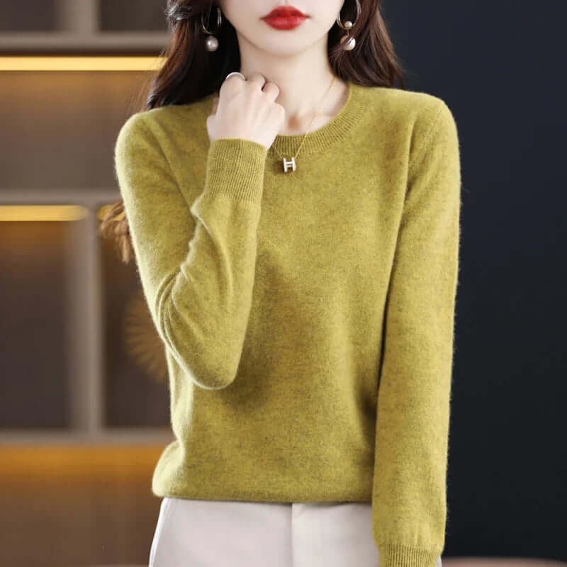 A model wears a lime green long-sleeved crew neck sweater, accessorized with a gold 'H' pendant necklace.