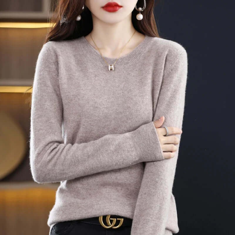 A model wears a light gray long-sleeved crew neck sweater, styled with a gold 'H' pendant necklace and a 'G' logo belt.
