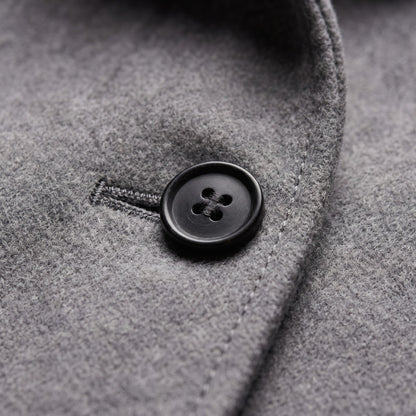 Close-up detail of a black button and buttonhole on the grey wool blend coat.