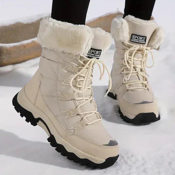 Front view of beige faux fur lined snow boots worn on feet in snow.