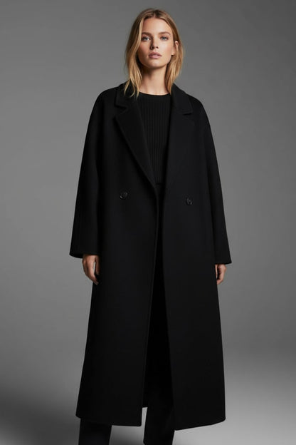 Front view of a woman wearing the black double-breasted longline coat open over a black sweater.